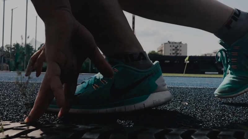 A Person Crouching on A Track, Wearing Nike Shoes, Preparing to Run