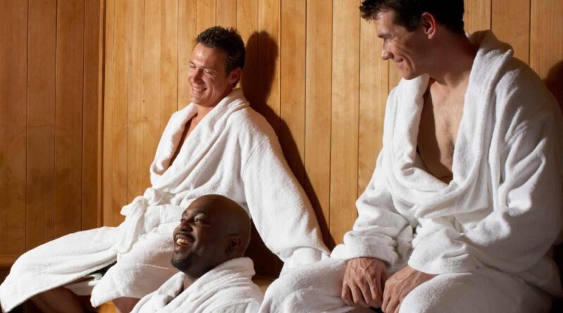 Three men sitting in a sauna in white robes