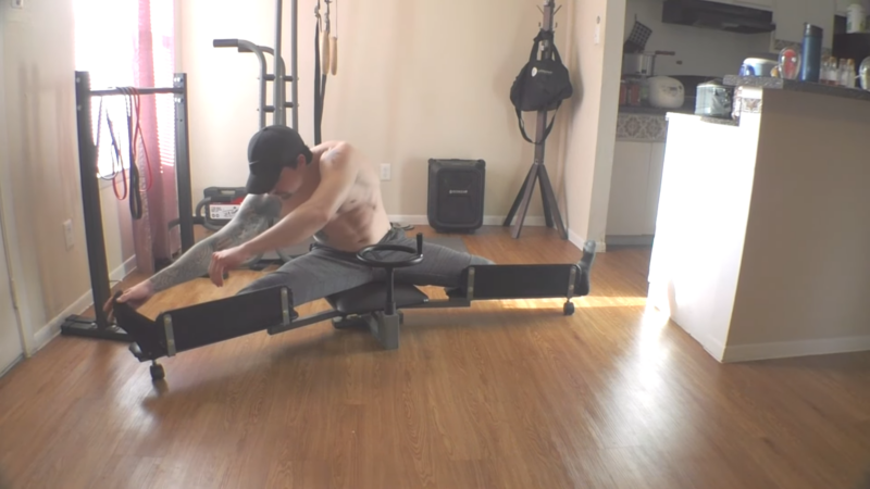 A Man Using the Zoomarlous Leg Stretch Machine