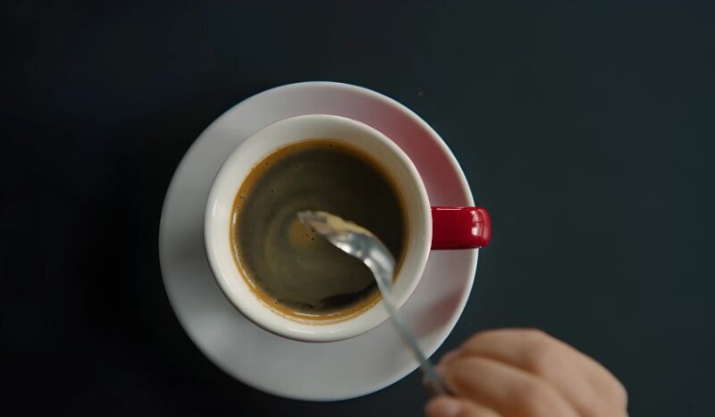 Person mixing coffee with a spoon