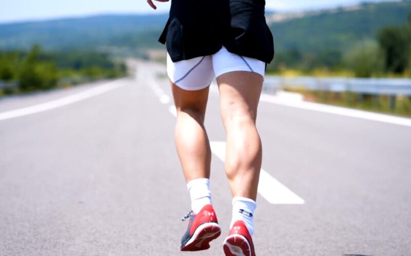 Runner photographed from the back, running on open road