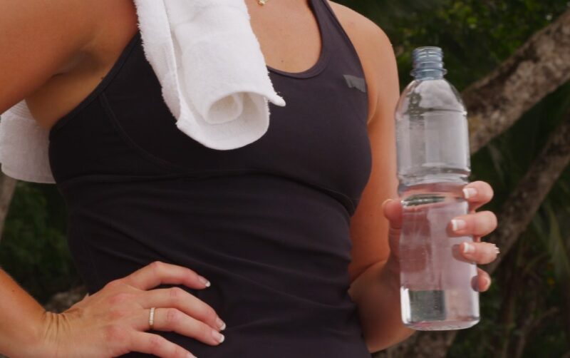 Woman holds bottle of water after training