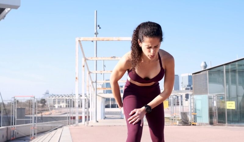 Female runner with hands on injured hamstring