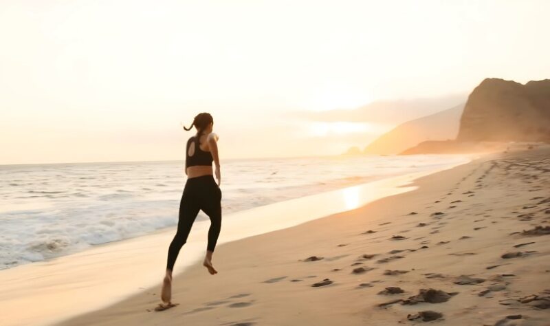 Woman running on a beach during sunset