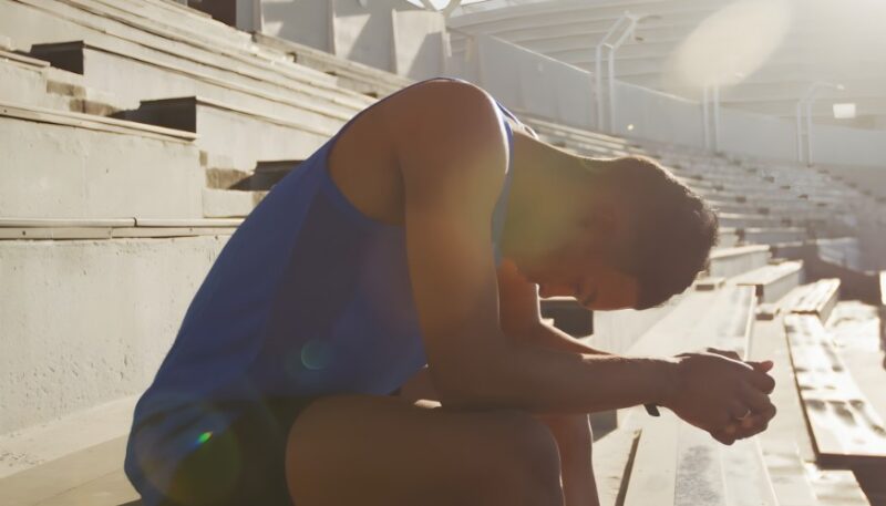 A runner sits slumped on stadium bleachers