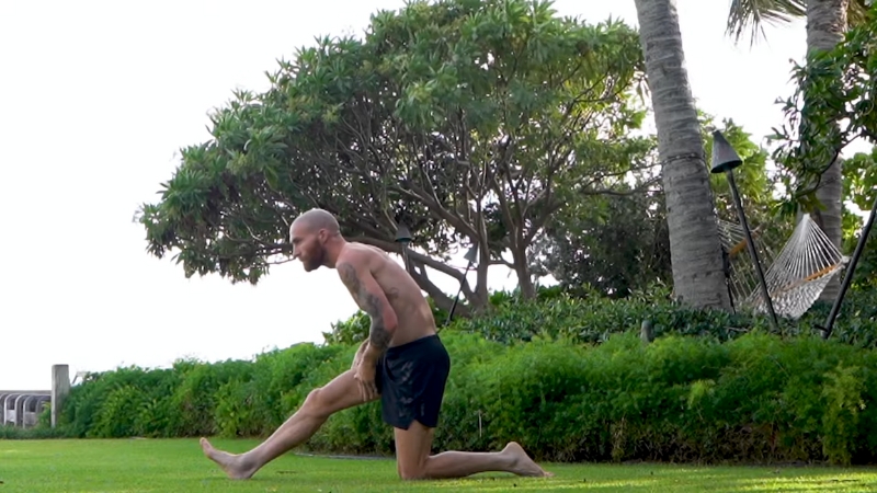 A Person Stretching Outdoors on Grass After a Workout