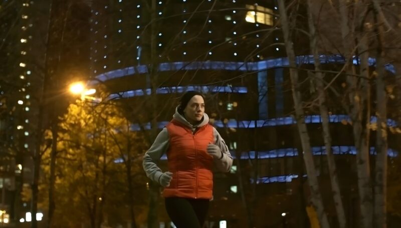 A woman jogging through a city park at night