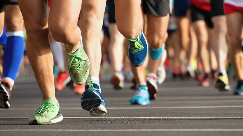 A Group of Runners in Colorful Shoes Participating in A Race on A Paved Road