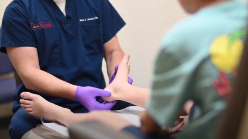 A doctor examines a child's foot, focusing on the ankle