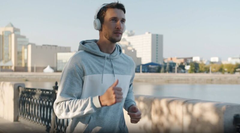 A man enjoys a brisk run along the waterfront, headphones on, taking in the city views