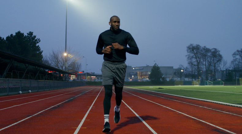 Urban athlete, fueled by the evening light. Effortless stride on the red track