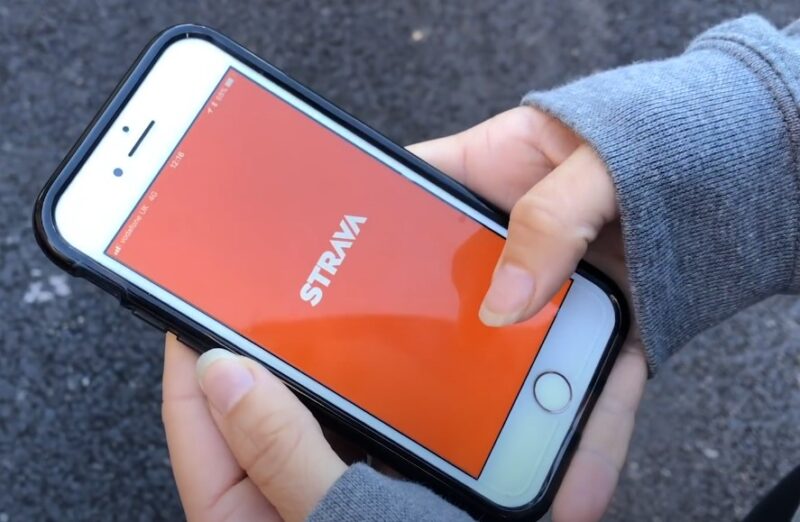 A woman holding her phone with STRAVA app opened