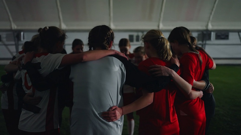 A group of young female soccer players huddling together in a circle before a game
