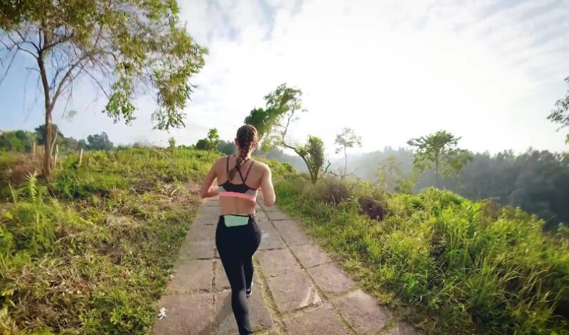A runner navigates a scenic trail, the path winding through lush greenery