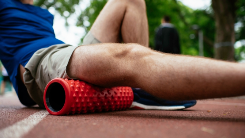 A person using a foam roller on their leg to aid in recovery after exercise