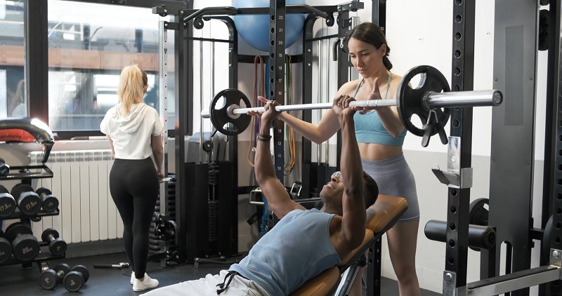 A woman spotting her training partner during a bench press exercise at the gym