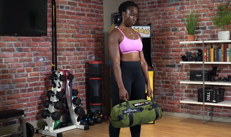 Woman lifting a heavy training bag in a home gym