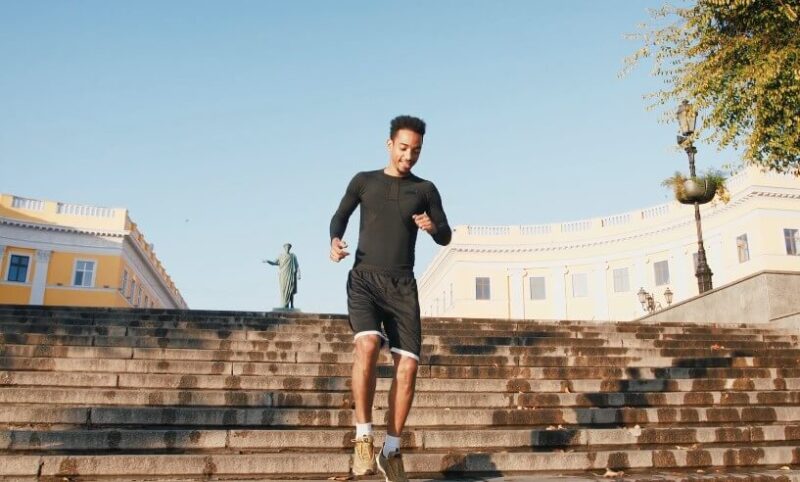 A man in athletic wear ascends a grand staircase