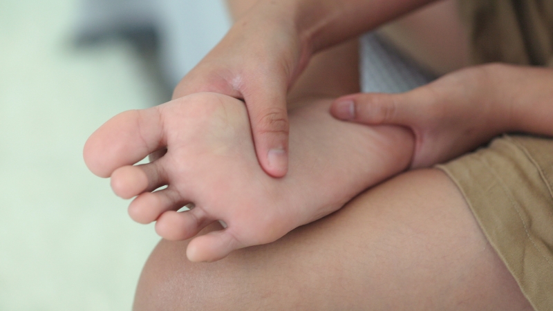 Person massaging the arch of their foot to relieve Plantar Fasciitis pain during recovery