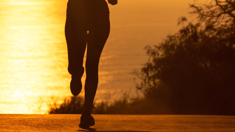 A person running outdoors during sunset, focusing on maintaining proper form despite tight hip flexors