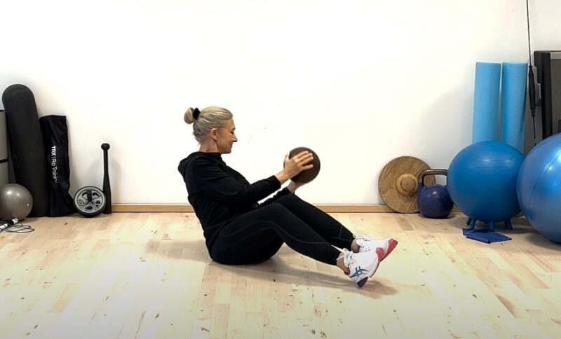 Woman performing a seated exercise with a medicine ball