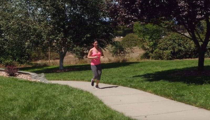 Sunlight warms the park as a woman runs