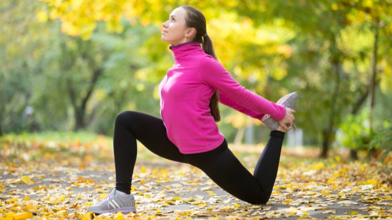 A person performing a stretch outdoors, focusing on improving flexibility and relieving tight hip flexors