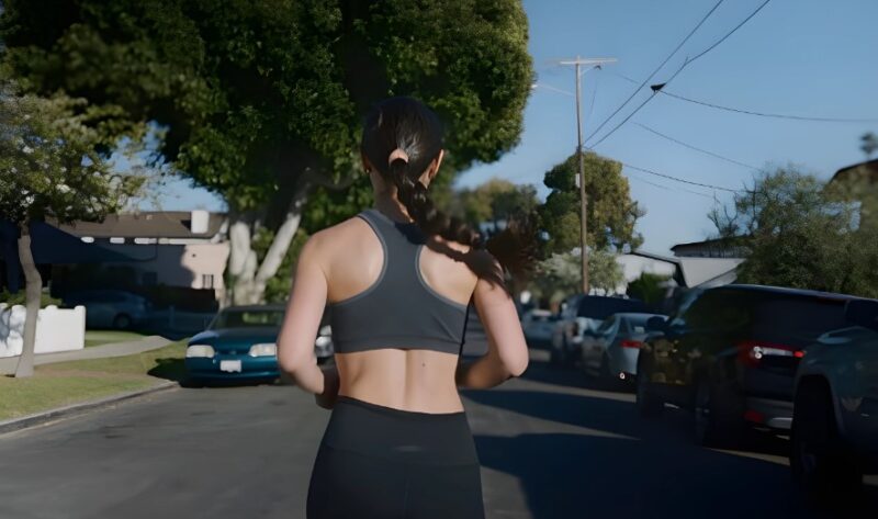 A woman runs down a residential street, sunlight warming her back