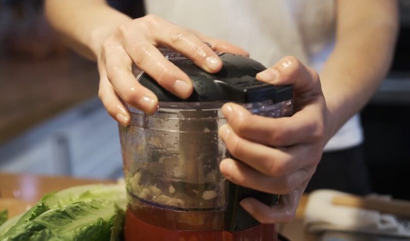 Close-up view of hands carefully placing the lid on a food processor