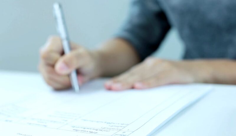 Close-up of hands filling out a form