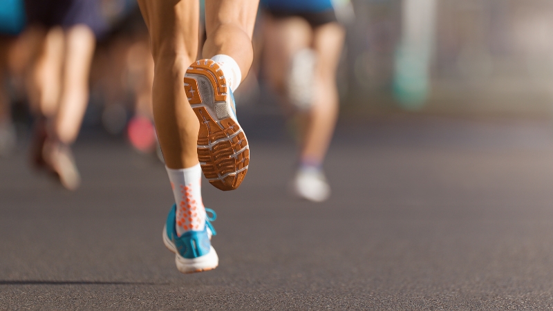 A close-up of runners' legs on pavement during a race, showing the physical effort involved in running a marathon