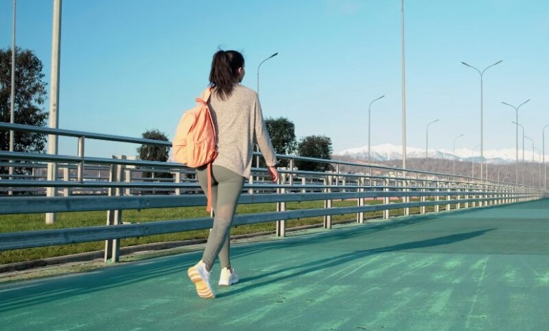 A woman strolls along a teal-colored walkway