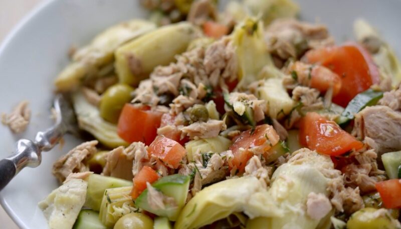 A vibrant medley of artichoke hearts, juicy tomatoes, crunchy cucumbers, and flavorful tuna