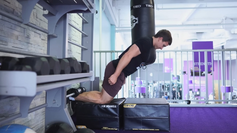 A person performs a Nordic hamstring curl exercise in a gym