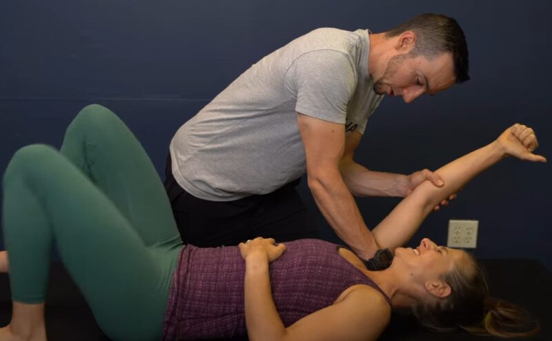 Physical therapist guiding a patient through a shoulder mobilization exercise