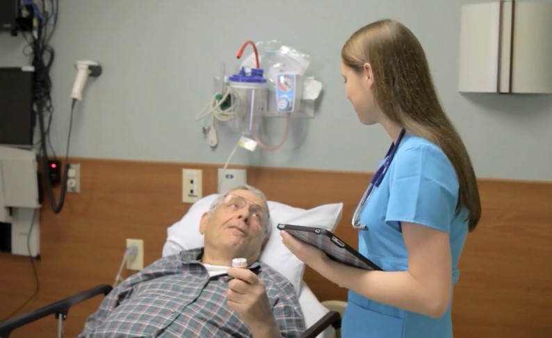 A nurse consults with a patient in a hospital room