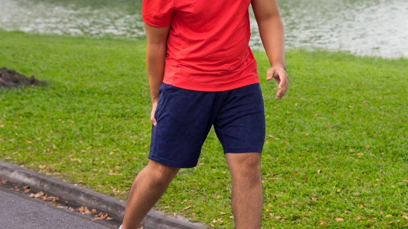 A person stands outdoors, holding the back of their thigh with a hand, suggesting a focus on hamstring health