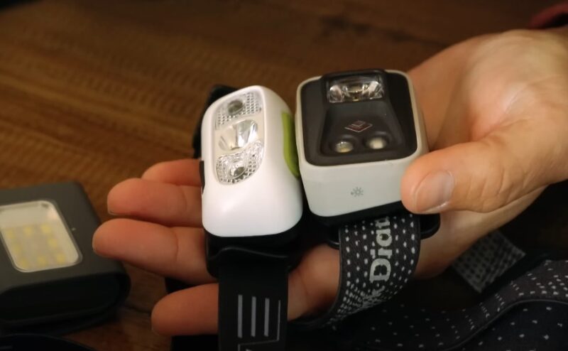 A hand holding a pair of headlamps for runners