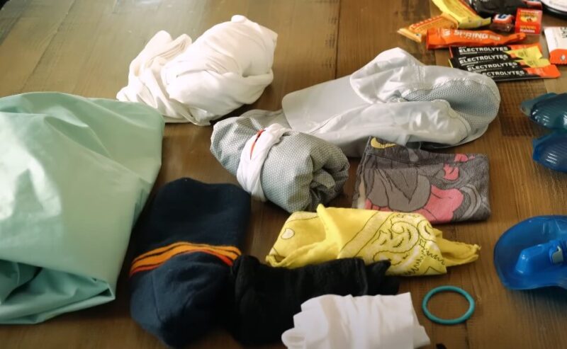 A table displaying a towel, socks, shoes, gloves, and multiple pairs of sunglasses