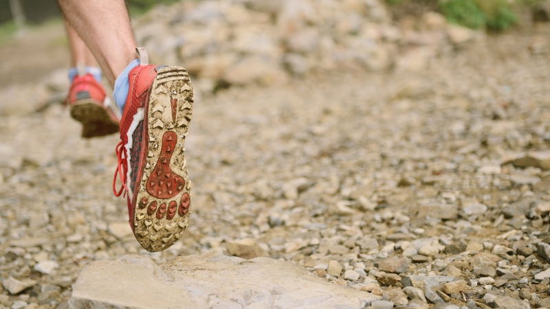 Runner's shoes on a rocky mountain trail, showing the demands of training and competing in high altitude running