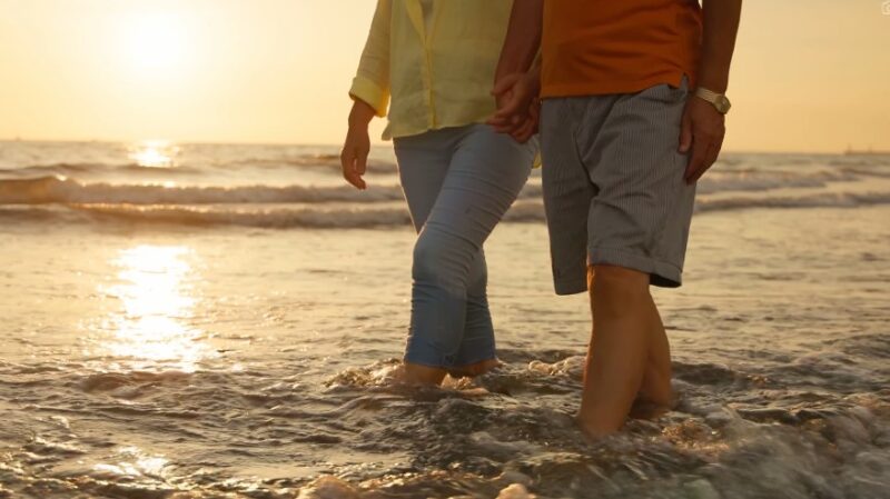 Couple walks hand-in-hand through the shallows at sunset