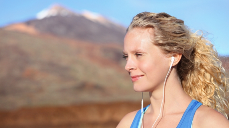 Woman listens to running playlists with earphones outdoors
