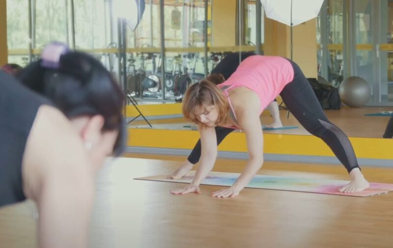 Women practicing yoga in a studio, focusing on a deep stretch