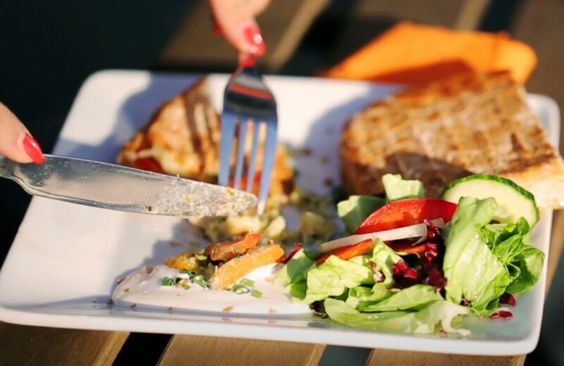 A plate of grilled sandwich, salad, and a creamy sauce