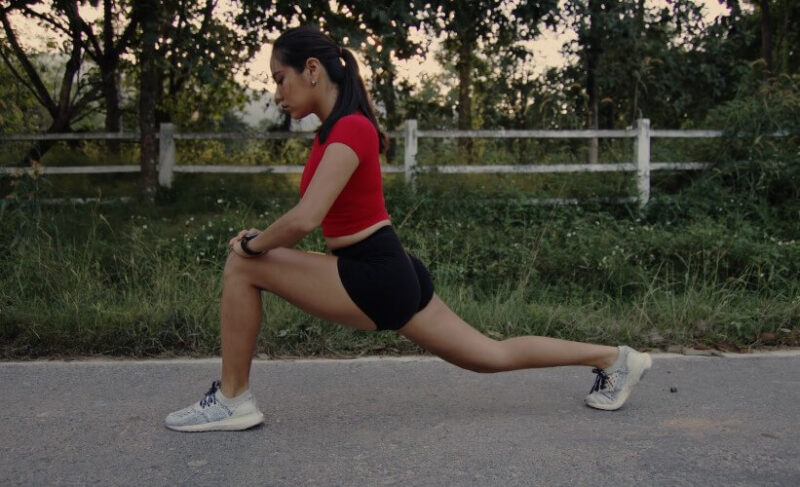 A woman stretches her leg, focusing on a deep hamstring stretch