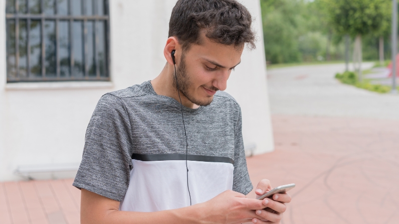 Man looks at his phone and selects music for an easy pace recovery run