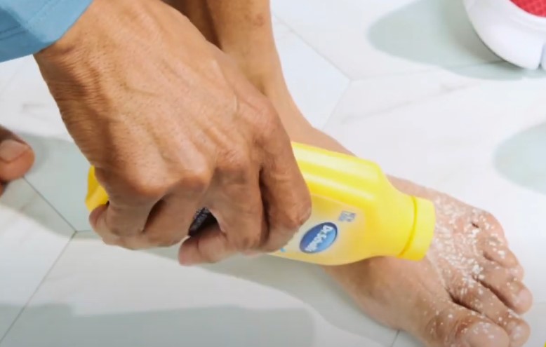 Applying foot powder to a foot with dry, flaky skin