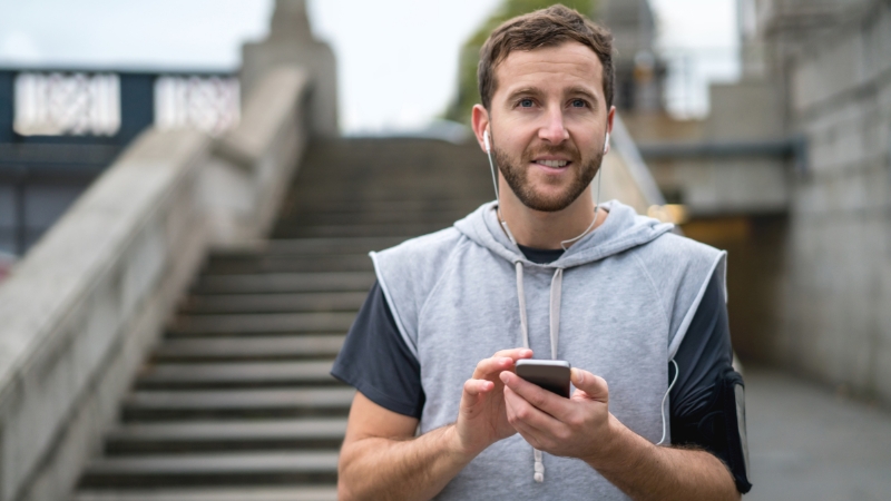 Man holds his phone and gets ready to build his own running playlist