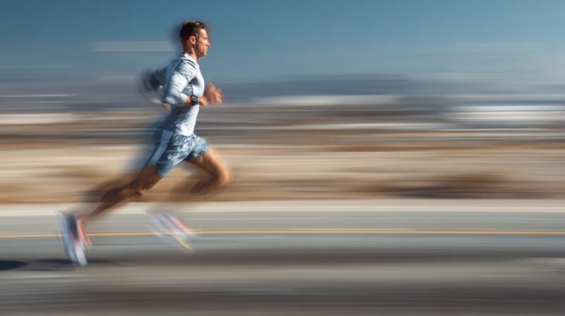 Runner in motion blur sprinting on a road with desert background