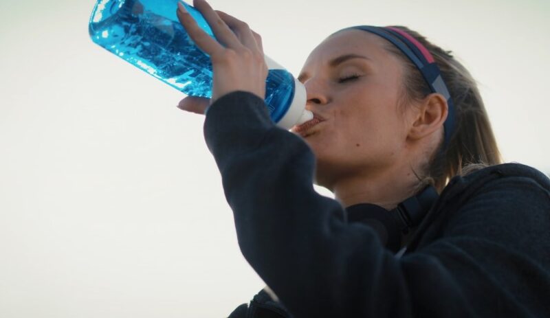 Woman taking a refreshing drink of water after a workout